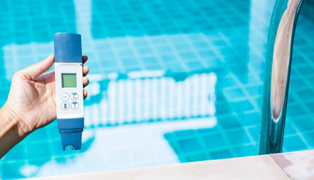 Digital water tester over blurred clear swimming pool water background, swimming pool service and maintenance, water tester technologyの写真素材
