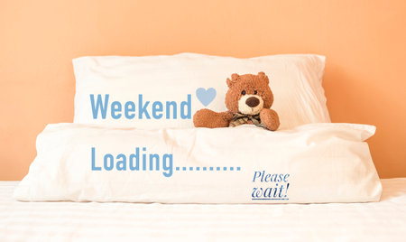 Weekend loading with brown teddy bear sitting in bed , weekend greeting card conceptの写真素材
