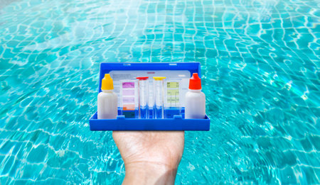 Water tester test kit in girl hand over blurred clear swimming pool water background, quality water test tool for swimming poolの写真素材