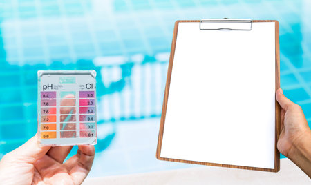 Swimming pool water testing test kit with blank report paper on wooden clipboard over clear pool water background, quality water tester technologyの写真素材