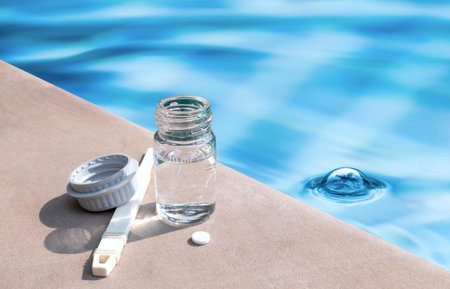 Swimming pool water testing equipment over blurred water background, quality water testing toolの写真素材