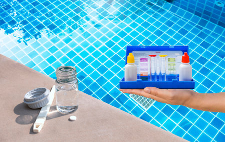 Swimming pool water testing equipment over blurred water background, quality water testing toolの写真素材