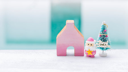 Pink Santa claus with wooden house and Christmas tree over blurred background, Christmas card background idea, outdoor day lightの写真素材
