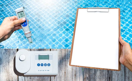 Digital swimming pool water tester with blank report paper on wooden clipboard over clear pool water...