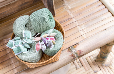 Natural color cotton thread roll in bamboo basket on bamboo bench, Thai organic cotton yarn roll with natural color dyedの写真素材