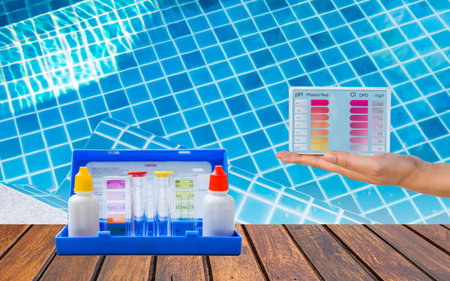 Water tester test kit on wooden table over blurred swimming pool water background, quality water testing test kit, pool maintenance and service business conceptの写真素材