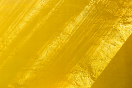 Yellow cement wall with morning day light background, shade on blank yellow wall backgroundの写真素材