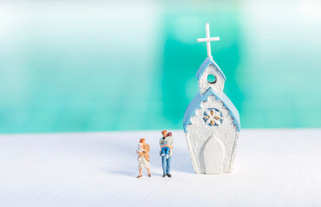 Miniature family with white Church over blurred background, religion concept