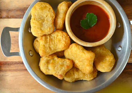 Chicken breast nuggets with tomato sauce on wooden