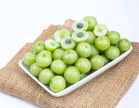 Indian gooseberry fruits or Amla berry ( phyllanthus emblica )  and sliced in white palte on white background.の写真素材