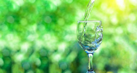 Pour water into a glass of water and bubble with the natural background. copy space