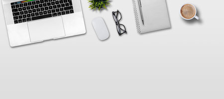 Laptop computer, notepad and coffee cup on white table. Top view