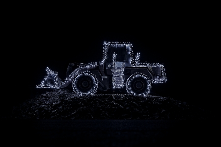 Blurred wheel loader decorated with lights in winter looks like a star sign in the skyの写真素材