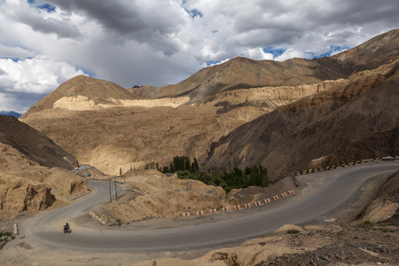 Beautiful Moonland surface near Lamayuru monastery with slope road and a motorbike in a cloudy day,Leh,Ladakh,Jammu and Kashmir,Indiaの写真素材