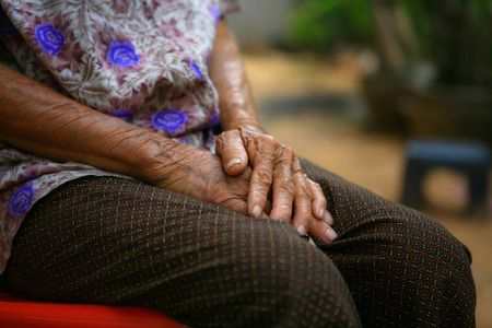 Those hands rock the cradle.Hands with wrinkle of an old woman showing experience,strength and endurance as a mother and grandmother who take care her children and niece.の写真素材