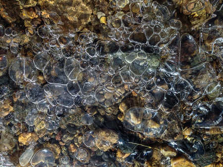 Transparent frozen air bubbles with stones and rocks at the bottom of canal in Tibet,China