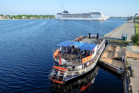 Ocean Cruise Ship MSC Opera turning round on Daugava river and Touristic river boat Pearl of Riga - Rigas perle - with paddle wheel by the Riga city embankement, Latviaのeditorial素材
