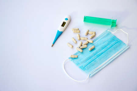 Thermometer, surgical mask, syringe and pills on a white backgroundの写真素材