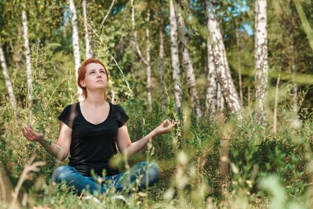 Girl teenager meditates in park and looking up.の写真素材