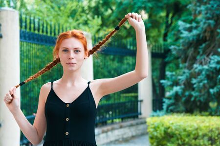 Cute redhead girl playing with hair outdoor. Fun and cheer concept.の写真素材