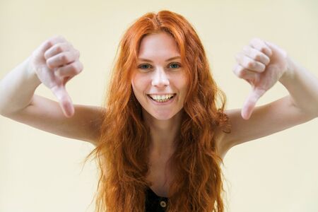 Beautiful ginger girl point thumbs down and smiling.
の写真素材