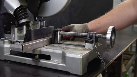 Working man with big saw cutting metal. Grinding in steel manufactory. 