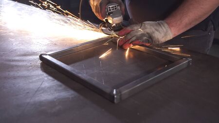 Grinding in steel manufactory. Working man with big saw polish metal.