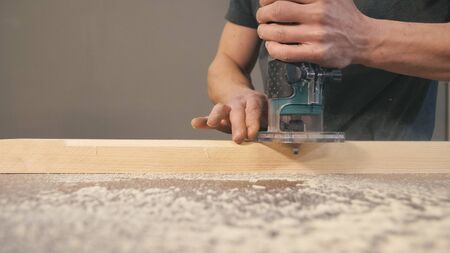 Worker bevel wooden board. Milling cutter and sawdust, closeup. Professional carpentry concept with copy space.の写真素材