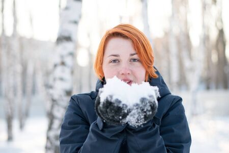 Girl with nordic appearance want to blow at snow in her hands. Winter holidays and joyful concept.の写真素材