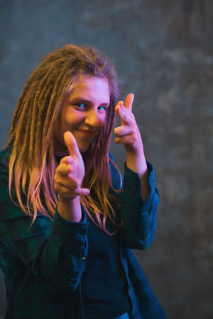 Young woman with dreadlocks in colorful neon lighting. Stylish girl on dark background.