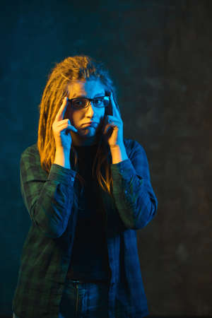 Girl with dreadlocks in colorful neon lighting on dark background. Stylish young woman in futuristic...