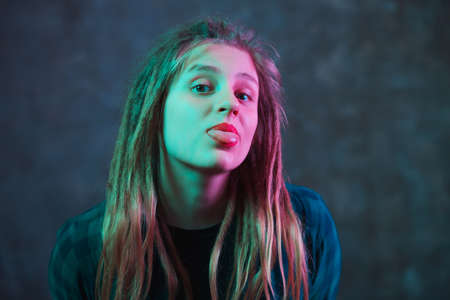 Girl with dreadlocks in colorful neon lighting on dark background. Stylish young woman in futuristic...