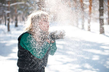 Woman blows at snow in her hands. Winter vacation concept. Unfocused image.の写真素材