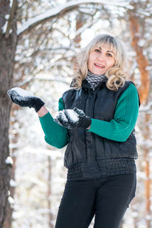 Adult woman plays snowballs in winter forest. Freedom and joyful concept.の写真素材