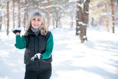 Adult woman plays snowballs in winter forest. Freedom and joyful concept.の写真素材