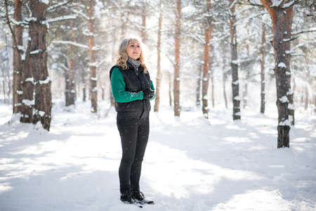 Walking in snowy forest. Beautiful woman in wintertime outdoor. Snowfall concept.の写真素材
