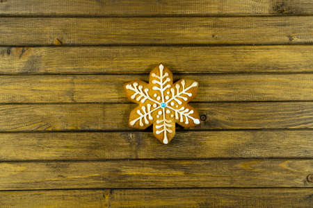 Gingerbread in shape of snowflake. Cookie on wooden background. Holiday concept with copy space.の写真素材