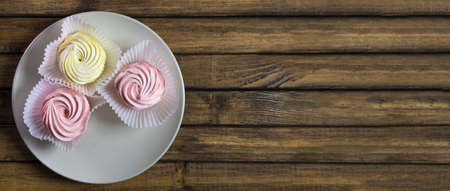 Food harmful to diabetics, soft focus. Sweet addiction concept. Meringue on plate at wooden background, copy space.の写真素材