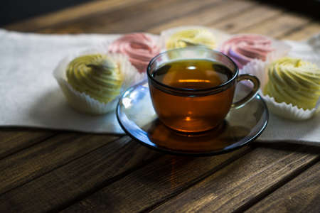 Mug of tea on wooden table, soft selective focus. Meringue on white napkin.の写真素材