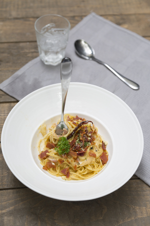 Dish of traditional spaghetti a la carbonara  with bacon  fork and spoon on table napkinの写真素材