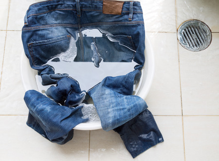 Jeans in water bucket on washing areaの写真素材