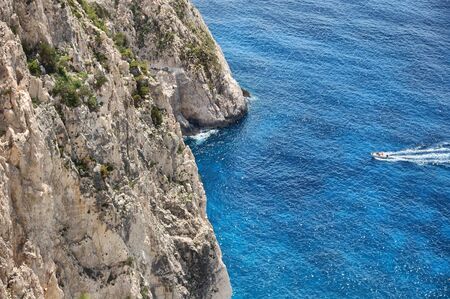 Small boat cruising through the Myzithres rocks passage in Zakynthos, Greece.の写真素材