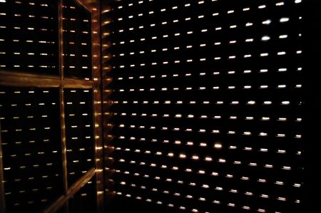 Light shining through a closed window shutter on a bright sunny day.の写真素材