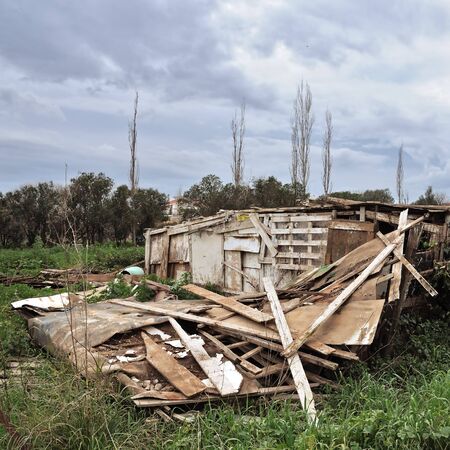 Collapsed old wooden hut and overcast sky.の写真素材