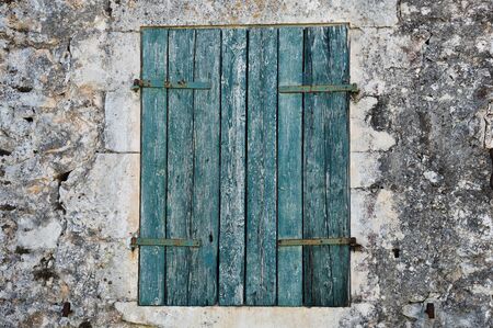 Stone wall and blue window shutter. Traditional house in Zakynthos, Greece.