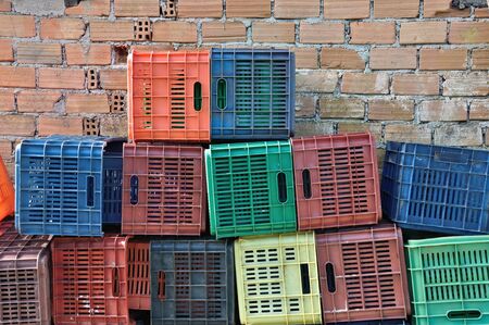 Plastic crates and brick wall background. Pile of colorful fruit packing containers.の写真素材