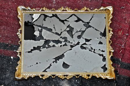 Antique golden picture frame with broken glass on dirty rag background.の写真素材