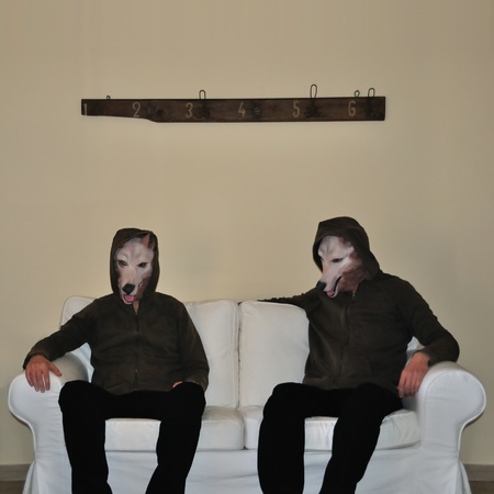 Two human figures with dog animal mask sitting on sofa couch. Two human figures with dog animal mask sitting on sofa couch.