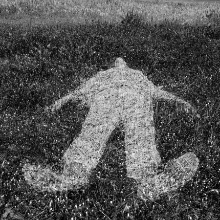 Reclining human figure outline imprinted on grass. Black and white.の写真素材