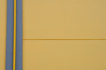 Yellow wall and drain pipe background. Abstract architectural detail.の写真素材